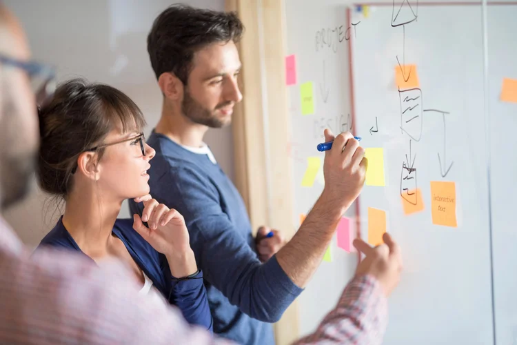 Two people working through a problem at a whiteboard